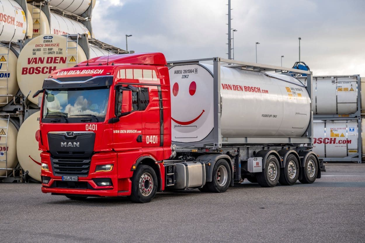 A red semi-truck, with a grey container attached, both with "Van den Bosch" branding.